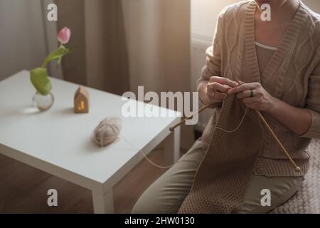 Les mains des femmes tricotage à partir de fils de laine beige Banque D'Images