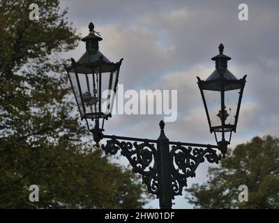 Vieux lanternes à gaz dans Kaiserswerth Allemagne bien entretenu et encore utilisé, un ciel nuageux, et des arbres Banque D'Images