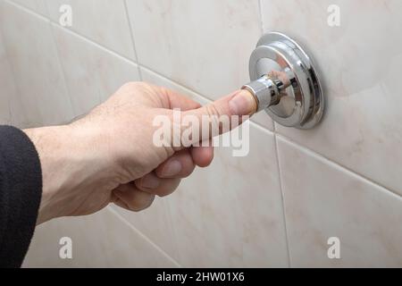 Main d'un homme poussant le drain des toilettes Banque D'Images