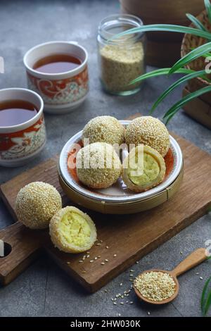 Onde de de onde ou gâteau de riz gluant boule de sésame sur plaque de céramique avec tasses de thé. Mise au point sélective, fond gris granuleux. Banque D'Images