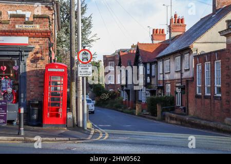 Vue sur une rue de village traditionnelle à Hawarden, dans le nord du pays de Galles, avec téléphone rouge Banque D'Images