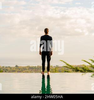 Un homme debout au bord de la piscine à débordement Banque D'Images