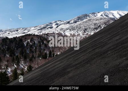 La cendre volcanique noire couvre un cratère de flanc sur le côté de l'Etna (3357m), en Sicile, en Italie, vu à la fin de l'hiver Banque D'Images