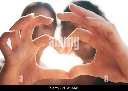 Nous nous sentons très bien sur cette île aujourd'hui. Photo courte d'un couple méconnaissable en forme de coeur avec les mains en étant debout sur la plage. Banque D'Images