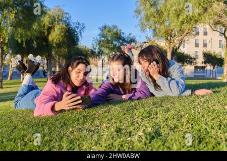 Trois amis prenant un selfie tout en étant allongé sur l'herbe portant des patins classiques Banque D'Images