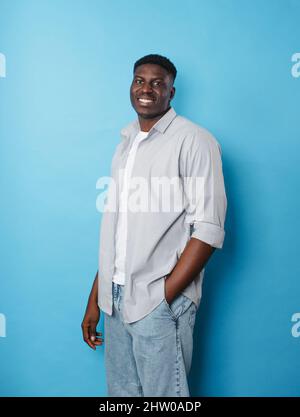 Un homme afro-américain vêque de vêtements blancs se tient sur un fond bleu isolé Banque D'Images