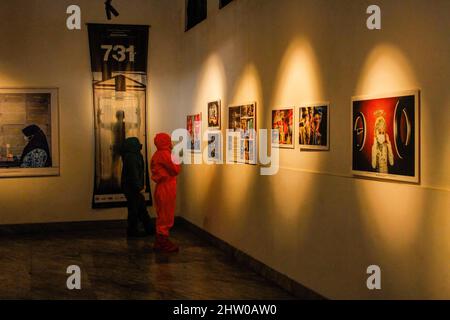 Bandung, Indonésie. 03rd mars 2022. Les visiteurs portant des combinaisons de protection contre les noisettes sont vus à l'intérieur de la Galerie lors de l'exposition pandémique de 371 jours à Bandung. Au total, 57 photos individuelles et quatre récits de photojournalistes indonésiens (PFI) Bandung ont été exposés à l'exposition de 371 jours de la pandémie en Indonésie, qui se tiendra jusqu'au 8 mars 2022. Crédit : SOPA Images Limited/Alamy Live News Banque D'Images