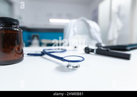 Accent sélectif sur le stéthoscope médical debout sur une table prête pour la consultation de la maladie. Vide bureau de médecin avec personne dans lui équipé d'outils d'examen professionnels. Concept de médecine Banque D'Images