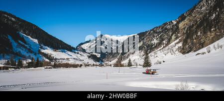 Panorama, tondeuse à neige ou chat de neige maintient un sentier de ski de fond sur une neige profonde et intacte en face des montagnes enneigées dans un concept de station de ski Banque D'Images