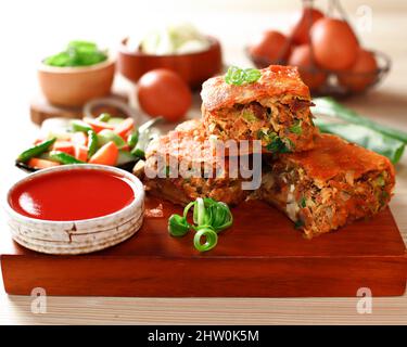 Indonésie cuisine traditionnelle de rue Martabak télur ou omelette murtabak, pâtisserie savoureuse poêlée farcie avec des œufs, de la viande et des épices à la sauce Rouge, Selec Banque D'Images