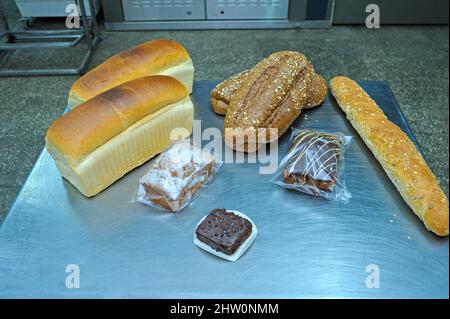 Produits de boulangerie néerlandais placés sur un plateau: Pain, petits pains, muffins, machines d'une ligne de pâte automatique sur le fond Banque D'Images