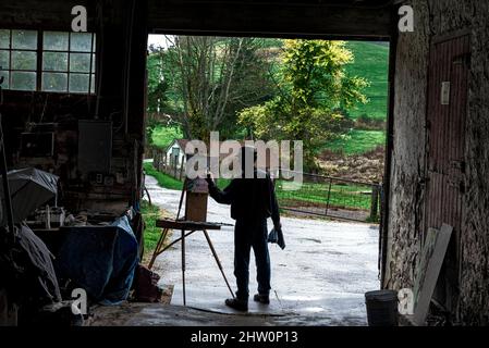 L'artiste peint un paysage rural à partir de la couverture d'une grange ouverte. Banque D'Images