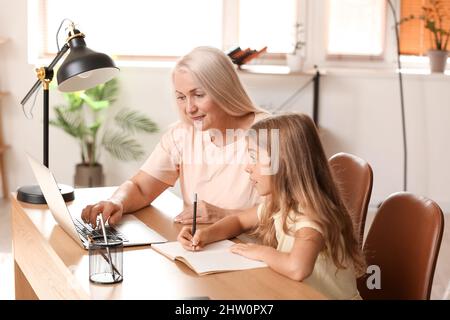 Petite fille avec sa grand-mère qui fait des leçons à la maison Banque D'Images