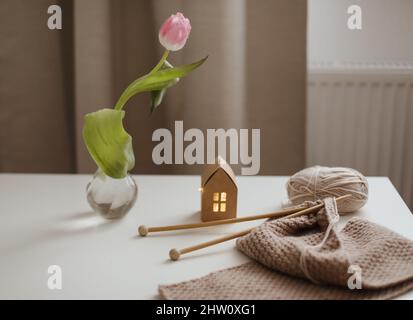 décoration intérieure chaleureuse avec chaise, tissu écossais, aiguilles de table et tricotage avec fils beige. Banque D'Images