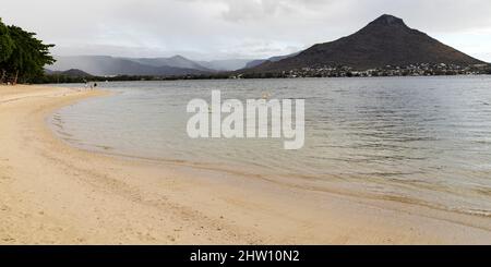 Vacanciers sur la plage de Flic en Flac à Maurice. L'eau de la baie de Tamarin fait le tour de la rive. Banque D'Images