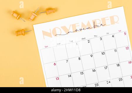 Calendrier de novembre 2022 et punaise en bois sur fond jaune. Banque D'Images