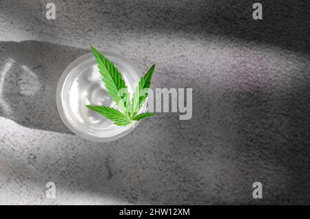 Cosmétiques naturels de chanvre. Soins du corps naturels. Hydratant à base de chanvre. Pot de crème corporelle et feuille de chanvre. Banque D'Images