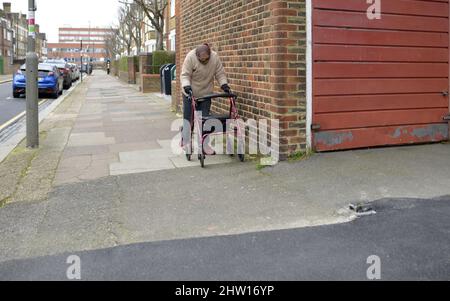 Londres, Angleterre, Royaume-Uni. Femme âgée utilisant un cadre de marche à roues à l'extérieur Banque D'Images