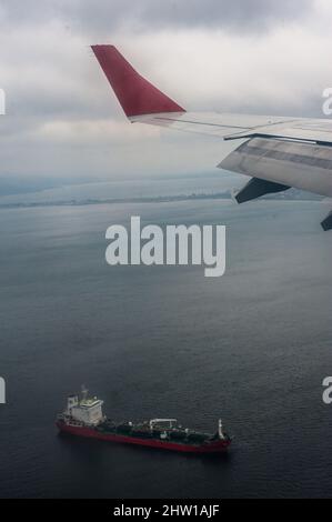 Vue depuis un avion de hublot d'une aile et d'un cargo en mer Banque D'Images