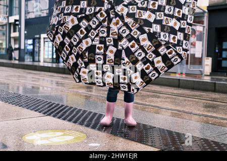 France, Finistère, Brest, par temps pluvieux, un enfant prend refuge sous un parapluie à l'arrêt de tramway rue de Siam Banque D'Images