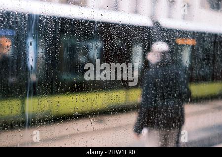 France, Finistère, Brest, homme à l'arrêt de tramway rue de Siam par temps pluvieux Banque D'Images