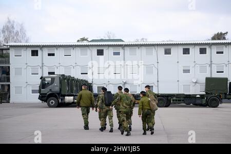Rukla, Lituanie. 03rd mars 2022. Des soldats du bataillon multinational du groupe de combat de la présence avancée renforcée de l'OTAN, dirigé par les Forces armées allemandes, marchent à côté de camions militaires sur la base militaire. Credit: Bernd von Jutrczenka/dpa/Alamy Live News Banque D'Images