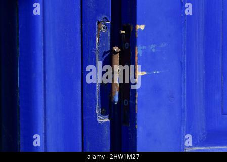 Ancienne maison rurale porte en bois bleu outremer avec peinture écaillée et charnière rouillée à Nafplio, Grèce. Banque D'Images