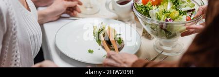 vue rognée d'une femme âgée avec salade de légumes et pinces de service, bannière, image de stock Banque D'Images