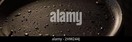 Fait partie d'une casserole vide en fonte de couleur noire avec des gouttes d'huile végétale. Gros plan. Arrière-plan sombre. Commencez la cuisson. Bannière Banque D'Images