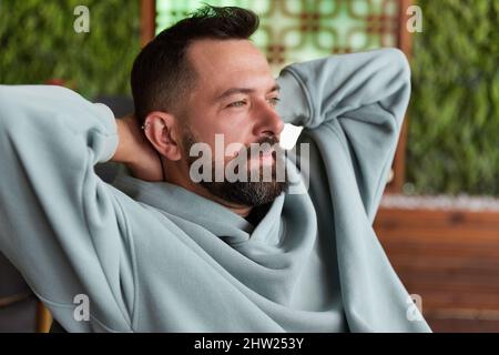 Un homme attrayant se détend au café et souriant. Un homme de style caucasien prend une pause de travail en ligne Banque D'Images