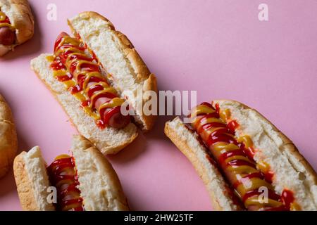 Vue en grand angle des sauces jaunes et rouges sur les hot dogs sur fond rose Banque D'Images