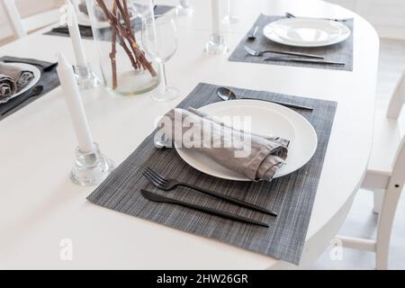 table à manger avec plaque blanche dans la maison moderne. branches en coton dans vase. Cuisine confortable.magnifique table avec des fleurs narcisses Banque D'Images