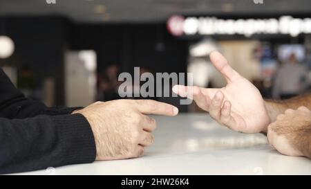 Gros plan sur les mains des hommes lors de négociations efficaces. Les mains de deux hommes se déplaçant pendant la conversation, le concept d'affaires et la conclusion d'un accord. Banque D'Images