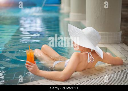 Débranchez, détendez-vous et détendez-vous. Photo d'une jeune femme se détendant avec un cocktail dans la piscine d'un spa. Banque D'Images