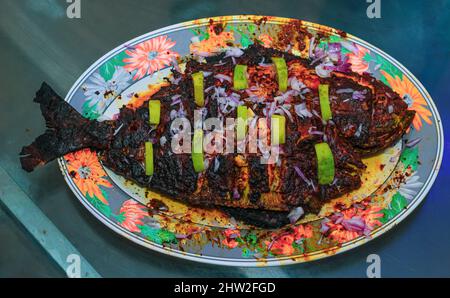 Poisson grillé, dorade avec ajout d'épices, d'herbes et de citron sur la plaque du gril. Banque D'Images