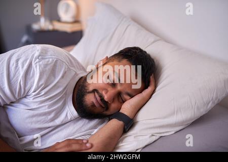 Un homme adulte dort paisiblement avec un sourire au lit le matin Banque D'Images