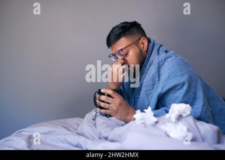 Un malade frotte ses sinus en s'asseyant au lit avec une boisson chaude. Copier l'espace Banque D'Images