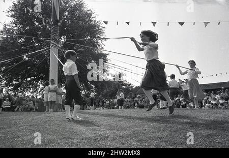 1987, les enfants qui se tiennent près d'un ruban pendant qu'ils dansent autour de la lypole, Popleton, Angleterre, Royaume-Uni. Danse folklorique cérémonielle autour d'un grand mât décoré de fleurs et de rubans, la danse de la lypole est une tradition ancienne datant des siècles aux danses autour des arbres pour célébrer l'arrivée du printemps. Au village vert de Popleton, York, les enfants de l'école primaire dansaient autour d'un typole chaque année depuis 1945. Banque D'Images