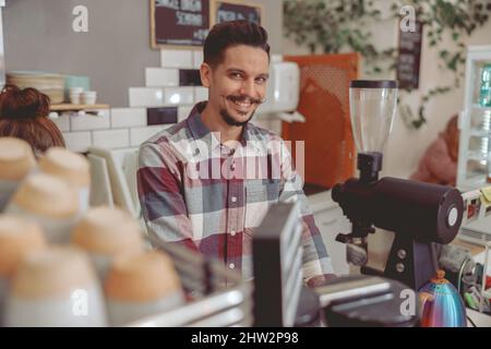 Un beau barista souriant avec une moustache à l'appareil photo Banque D'Images