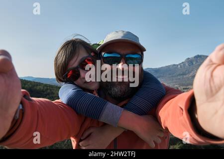 Un adolescent avec des bretelles et un père prenant le selfie pendant la randonnée dans la nature Banque D'Images
