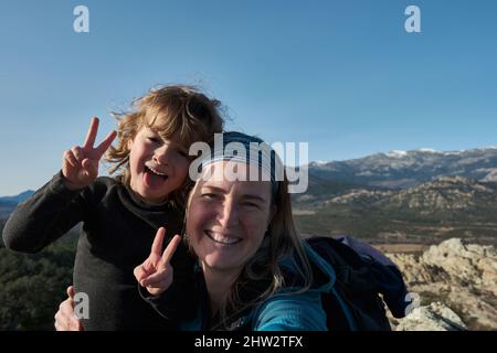 Mère et fils prennent des selfies dans la nature, le garçon grimace et montre sa langue. Banque D'Images