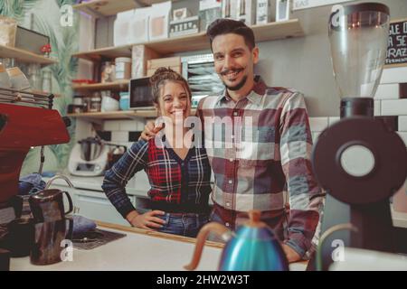 Belle femme et homme portant une chemise à carreaux debout dans un café au bar Banque D'Images