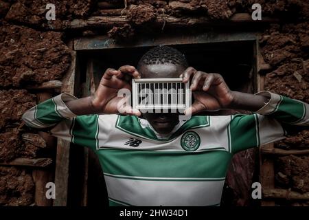 Un jeune garçon tient un mini panneau solaire portable dans les bidonvilles de Kibera, Nairobi. Des milliers de ménages dans les bidonvilles de Kibera au Kenya dépendent de l'électricité comme principale source Banque D'Images