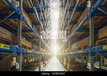 Immense entrepôt industriel moderne, vue sur le couloir avec lumière à l'extrémité. Boîtes de marchandises et de produits prêtes pour la distribution et la logistique. Banque D'Images