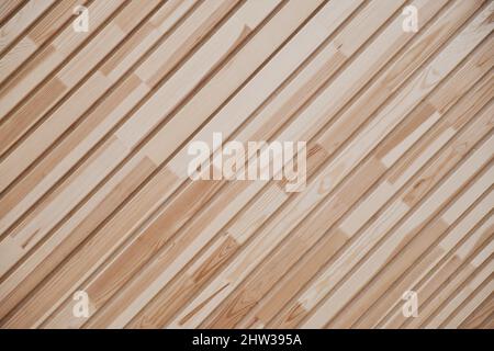 Gros plan sur le mur des panneaux. Fragment de planches diagonales en bois. Décoration de matériaux. Texture du bois comme arrière-plan. Banque D'Images