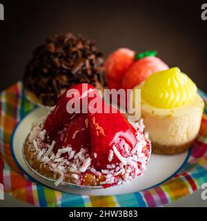 Cliché sélectif carré d'une tarte aux fraises sur une assiette colorée avec une variété de desserts Banque D'Images