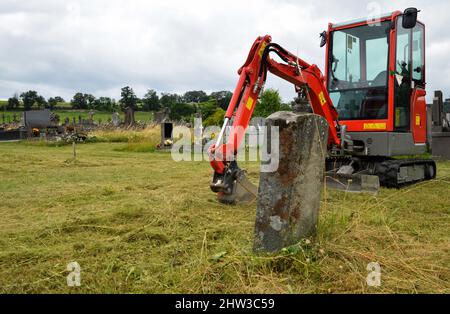 Une pelle hydraulique pour creuser une tombe dans un cimetière pour l'enterrement ou l'exhumation. Banque D'Images