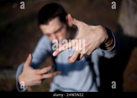 Un jeune homme montre des gestes avec ses mains. Le gars montre des mouvements avec ses doigts. Sous-culture de la jeunesse. Grand homme d'apparence européenne. Un dre moderne Banque D'Images