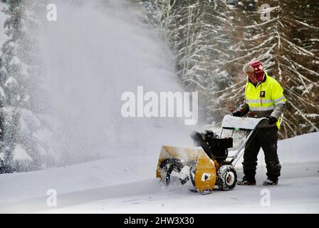 Homme déneigement avec un souffleur de neige pendant une tempête à Villars sur Olllon en Suisse Banque D'Images