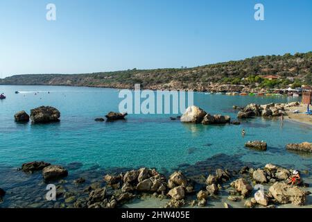 Eaux cristallines bleu de la mer Méditerranée et rochers jaunes sur la plage de sable de Konnos près de Protaras, Chypre Banque D'Images